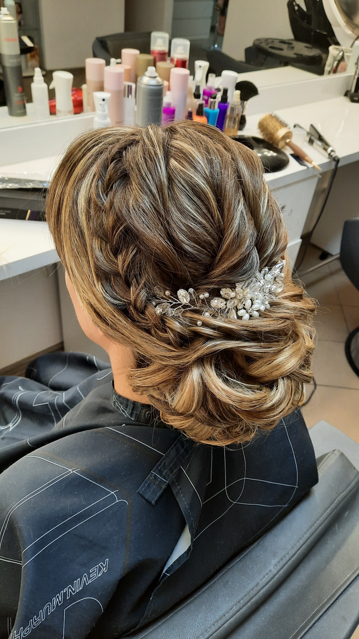 Elegancka fryzura ślubna z wpiętą ozdobą z pereł i kryształków, wykonana w salonie fryzjerskim w Kutnie, widok z tyłu na upięcie z blond pasemkami.