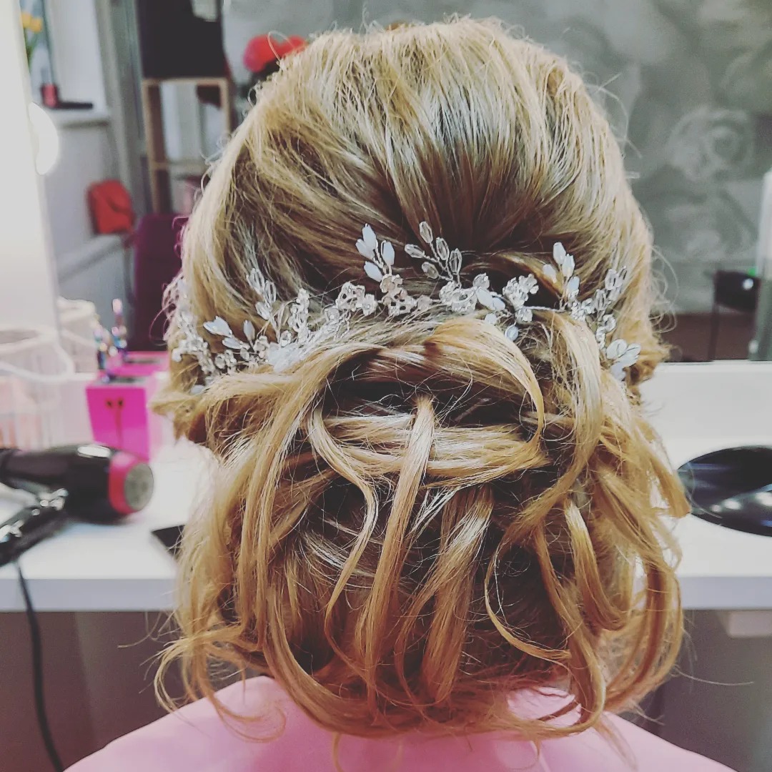 Upięcie ślubne z blond włosów z ozdobnym srebrnym wiankiem z kryształkami i kwiatkami, widok z tyłu.