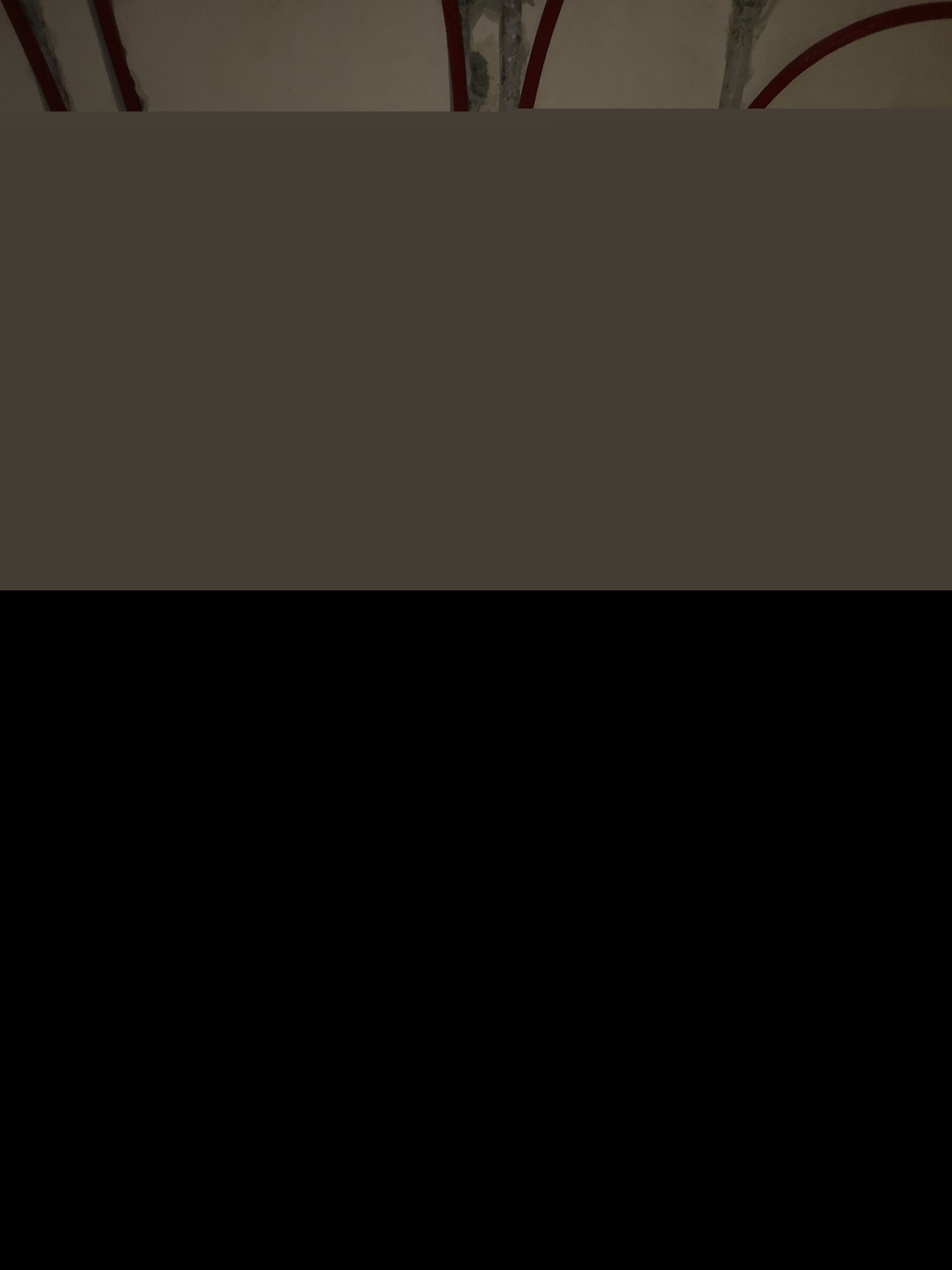 Fragment sufitu z widocznymi elementami konstrukcyjnymi i śladami prac wykończeniowych, zarysowane czerwone łuki dekoracyjne.