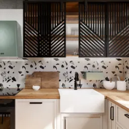 Nowoczesna kuchnia z drewnianym blatem, białymi szafkami, czarną armaturą i backsplashiem w stylu lastryko, uzupełniona o dekoracyjne przesuwne panele z geometrycznym wzorem.