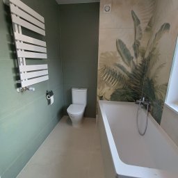 Torem Tomasz Mokras - Nowoczesna łazienka z zielonymi ścianami, białym grzejnikiem drabinkowym, toaletą i wanną z motywem roślinnym na płytkach. Minimalistyczny design.