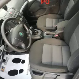 Wnętrze samochodu w Barcinie z szarymi fotelami i papierową matą podłogową z nadrukowanymi śladami stóp.