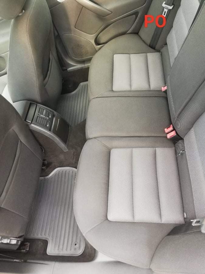 Wnętrze samochodu z widocznymi tylnymi siedzeniami i nowymi, szarymi dywanikami; tapicerka siedzeń w odcieniach szarości z wyraźnymi przeszyciami.