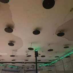 Przygotowanie do montażu sufitu napinanego: widok na sufit z zamocowanymi elementami mocującymi, laser krzyżowy wyznacza poziom, widoczne fragmenty starej powierzchni sufitu.