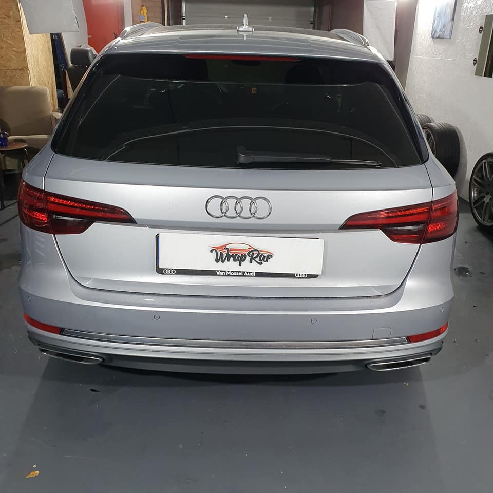 Srebrne Audi kombi z przyciemnionymi szybami tylnymi, widok z tyłu, tablica z logo firmy 'Wrap Rar Van Mossel Audi'.