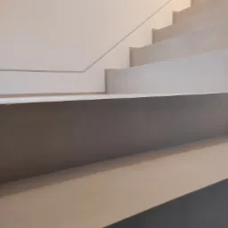 Schody wykończone jasnym, gładkim materiałem, prawdopodobnie mikrocementem, z minimalistyczną barierką w tle.