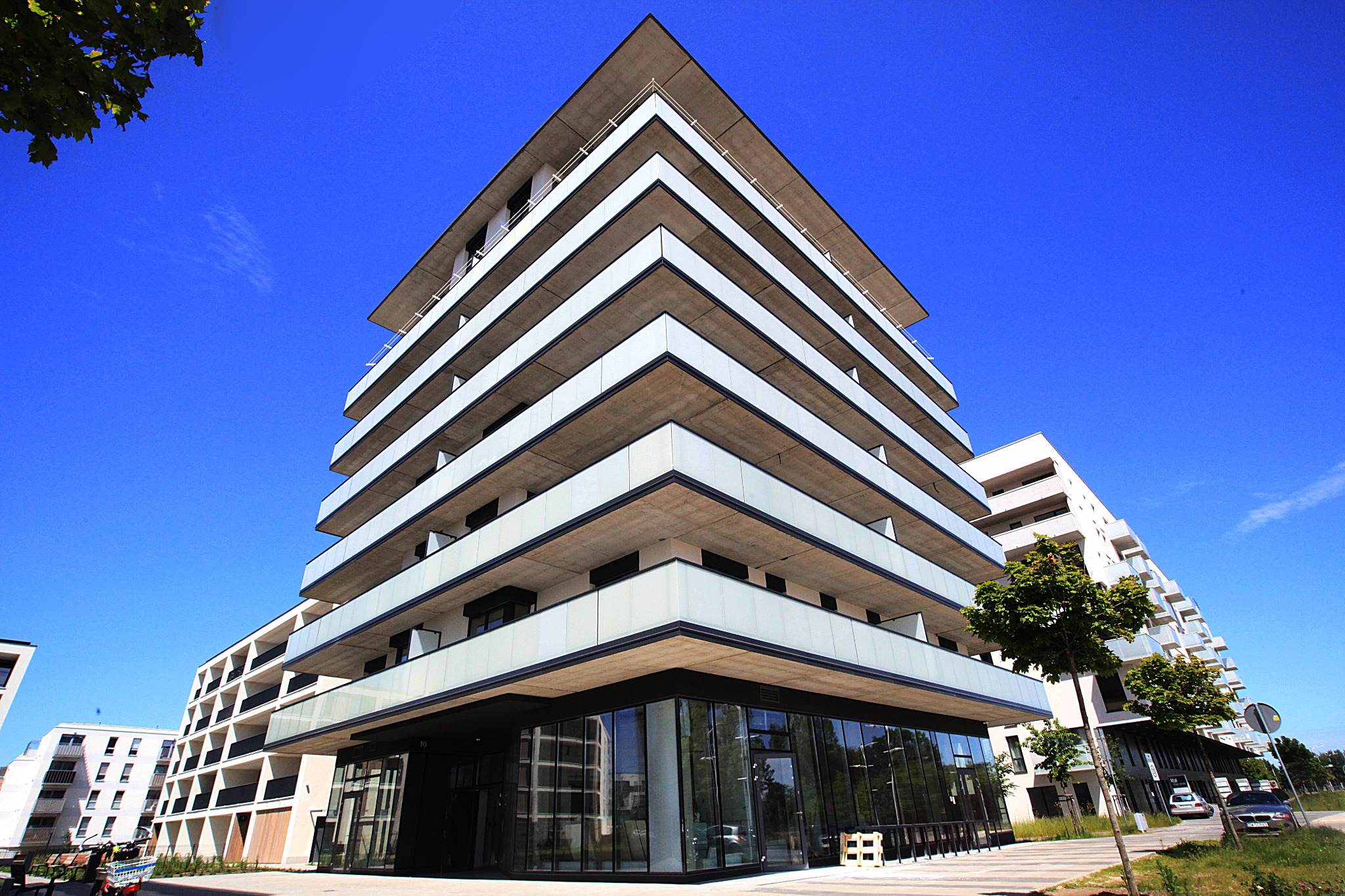 Nowoczesny budynek apartamentowy z balkonami, widok z dołu na błękitne niebo.