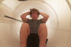 Mężczyzna z rękami za głową siedzi wewnątrz białej, cylindrycznej komory hiperbarycznej, patrząc w górę.