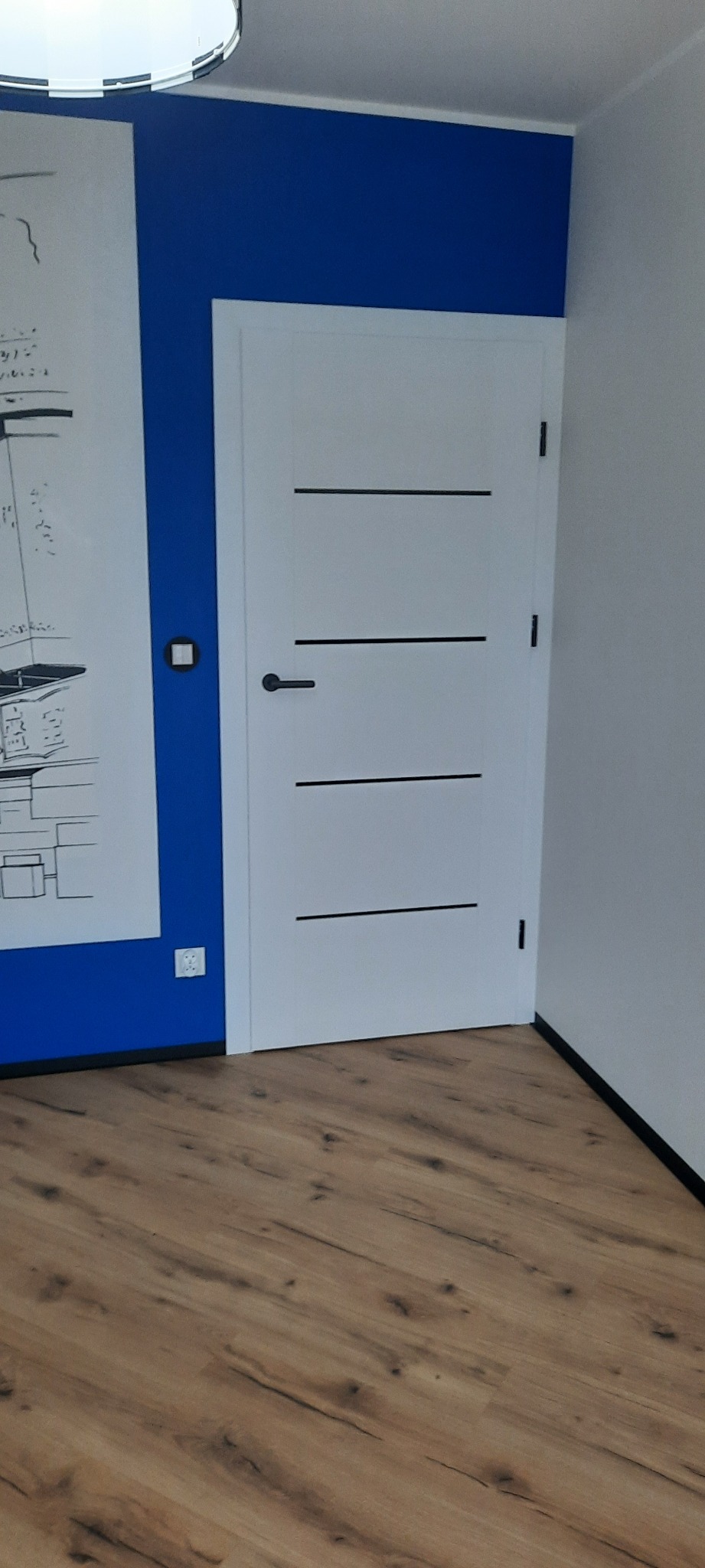 Białe drzwi z czarnymi, poziomymi paskami na tle niebieskiej ściany z rysunkiem i drewnianej podłogi. Minimalistyczny design.