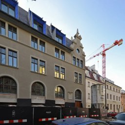 R&R Development - Budynek w trakcie renowacji z widocznym żurawiem budowlanym w tle, zabezpieczenia na dole fasady, okna z kratami.