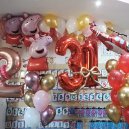 Dekoracja balonowa na 30 urodziny z motywem Peppy Pig i helikoptera, z balonami w kolorach różowym, złotym, białym i czerwonym, na tle ściany z opakowaniami balonów z cyframi.