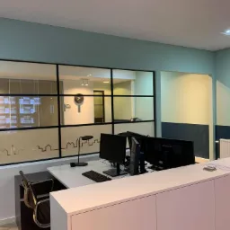 Nowoczesne biuro z recepcją, przeszkloną ścianą z motywem miasta i dwoma monitorami na biurku.