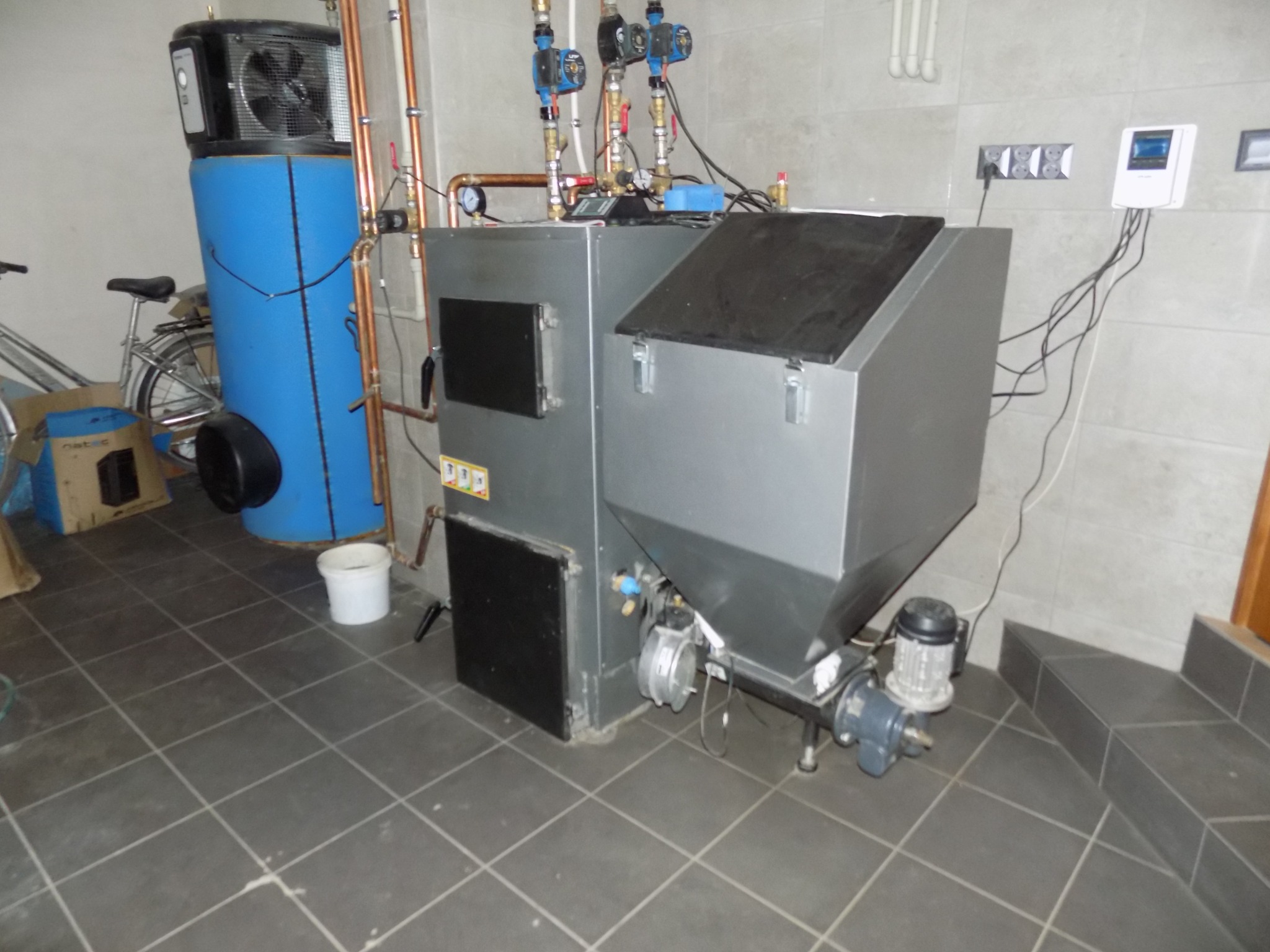 Kłobuck: Kotłownia z piecem na ekogroszek, zasobnikiem C.W.U. i powietrzną pompą ciepła, widoczne trzy obiegi grzewcze C.O., C.W.U. i ogrzewanie podłogowe, całość zainstalowana na ciemnej podłodze...