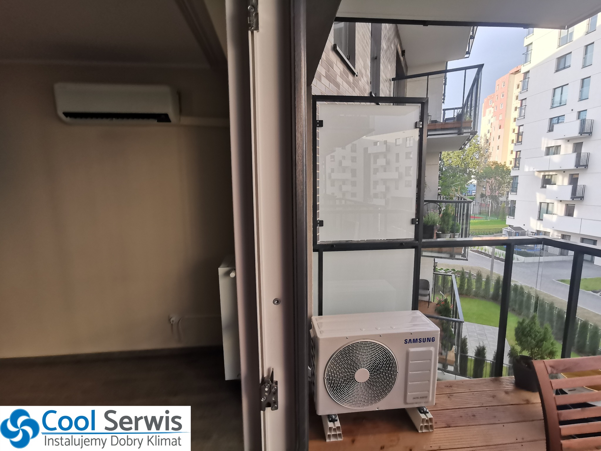 Zamontowana jednostka zewnętrzna klimatyzacji Samsung na balkonie mieszkania w bloku, widok z wnętrza pomieszczenia przez otwarte drzwi balkonowe, druga jednostka wewnętrzna zamontowana na ścianie...