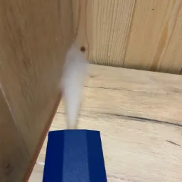 Dym unoszący się z niebieskiego urządzenia na tle drewnianej ściany.