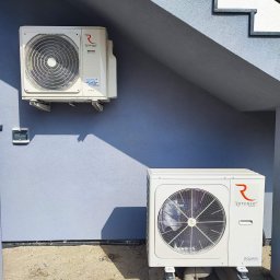 Nortmar Power Systems Centrala - Dwie jednostki zewnętrzne pompy ciepła Rotenso Aquami zamontowane na szarej ścianie budynku z widocznymi schodami zewnętrznymi, dolna jednostka stoi na betonowych blokach, a górna jest przymocowana...