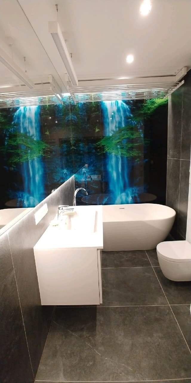 Nowoczesna łazienka z wanną wolnostojącą, umywalką nablatową i fototapetą z motywem wodospadu na ścianie.