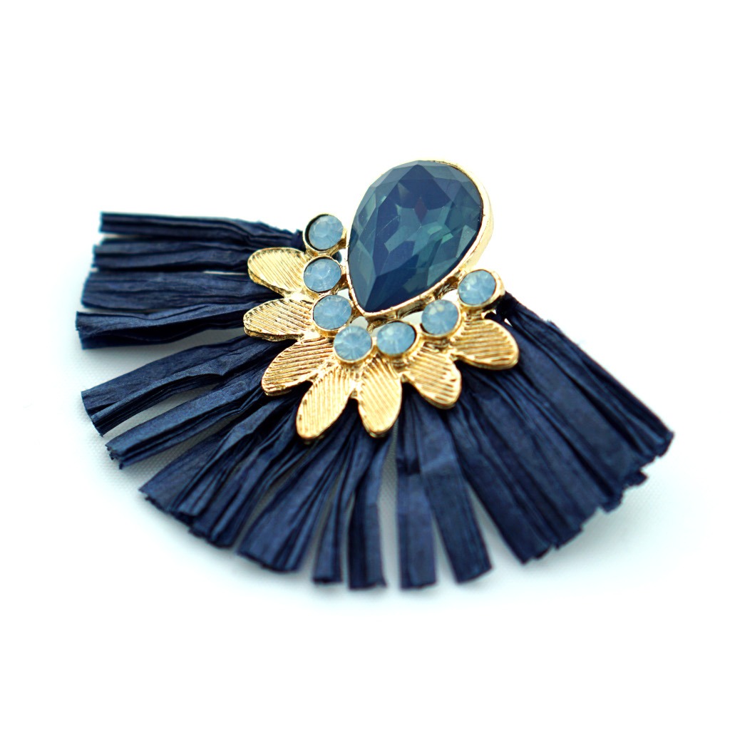 Kolczyk typu tassel w kolorze granatowym z elementami złota i niebieskich kryształów na białym tle.