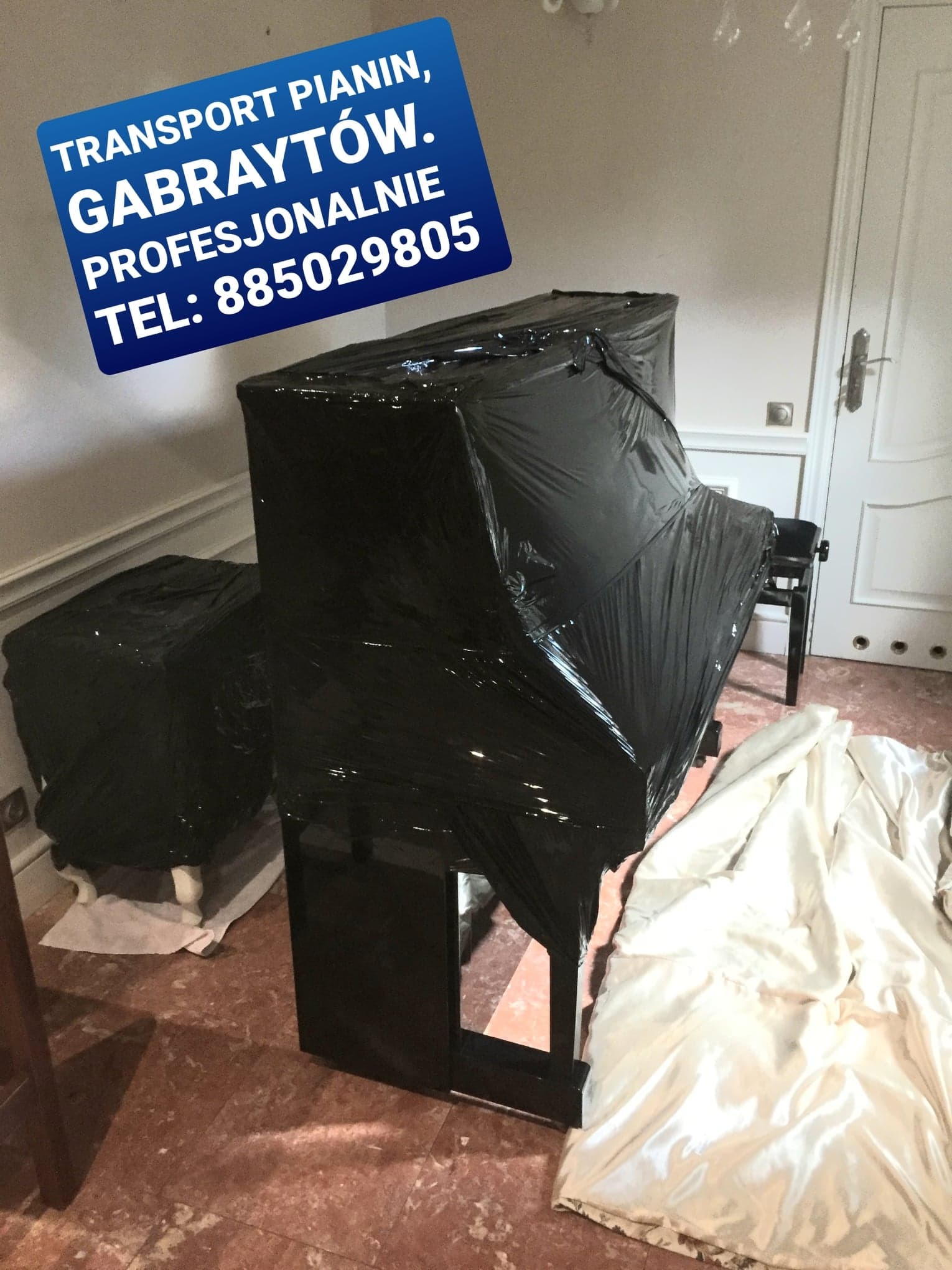 Pianino zabezpieczone czarną folią stretch, przygotowane do transportu, obok widoczny plakat informacyjny z danymi kontaktowymi firmy transportowej.