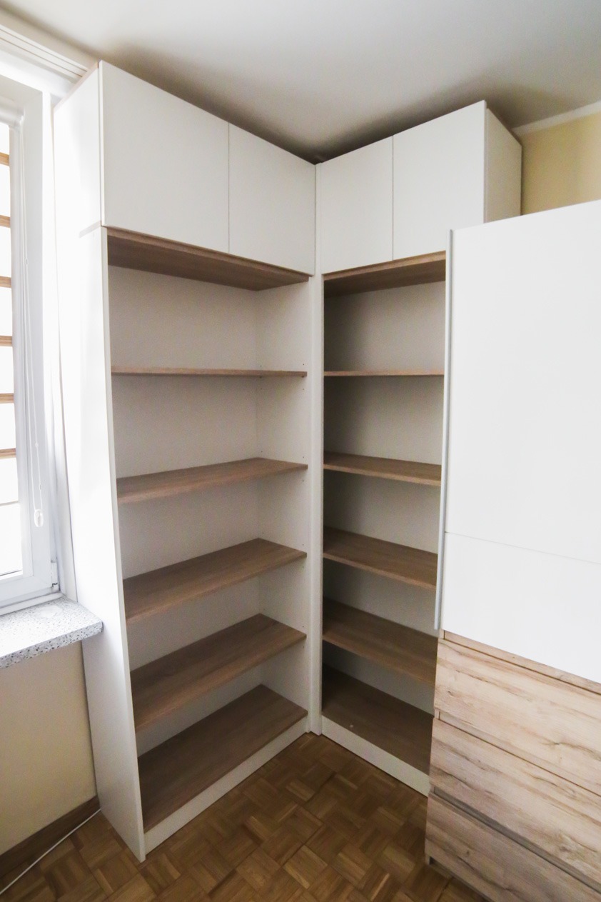 Biała szafa narożna na wymiar z drewnianymi półkami, widok z bliska na puste wnętrze i parkiet na podłodze