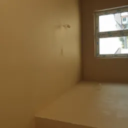 Świeżo położone, jednolite tynki na ścianach w pomieszczeniu z oknem PCV marki VEKA, widoczne wystające kable instalacji elektrycznej.