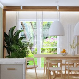 LU Design Luiza Paluch - Jasna jadalnia z parkietem w jodełkę, drewnianym stołem i krzesłami. Za stołem okno z widokiem na ogród. Na stole owoce i wazon. Minimalistyczny design.