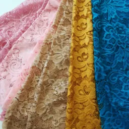 Różowe, beżowe, złote i niebieskie koronki leżące obok siebie, ukazujące delikatny wzór kwiatowy i ażurową strukturę.