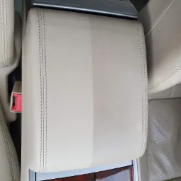 Skórzany podłokietnik samochodowy, widoczna różnica w czystości pomiędzy wyczyszczoną, jaśniejszą połową a brudniejszą, ciemniejszą częścią.