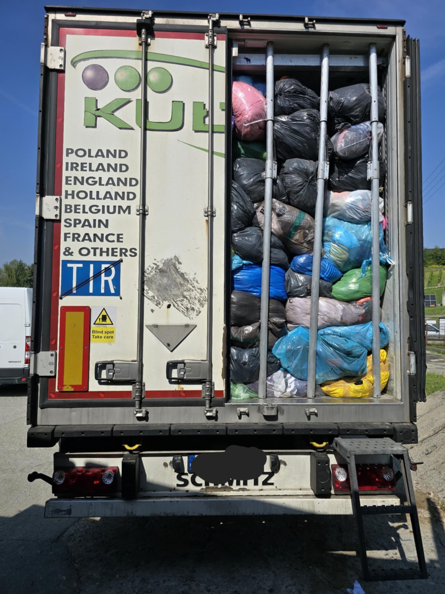 Ciężarówka z otwartymi drzwiami, wypełniona workami z odzieżą, prawdopodobnie używaną, w Kalwarii Zebrzydowskiej. Widoczne logo firmy transportowej i oznaczenia TIR.