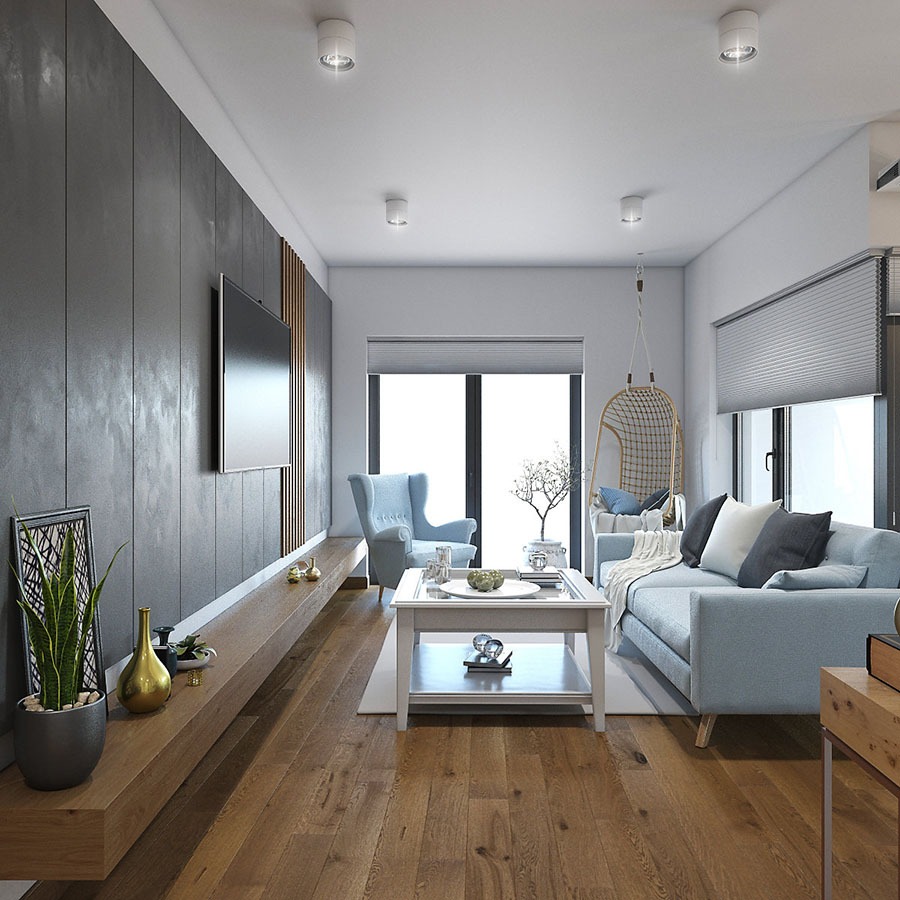 Nowoczesny salon z drewnianą podłogą, szarą ścianą z telewizorem, błękitnym fotelem i sofą oraz wiszącym fotelem typu huśtawka. Na niskiej szafce RTV złota figurka i roślina w doniczce.