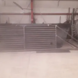 Metalowa konstrukcja bramy w trakcie produkcji, widoczne profile i elementy spawane, surowe wykończenie w hali produkcyjnej.