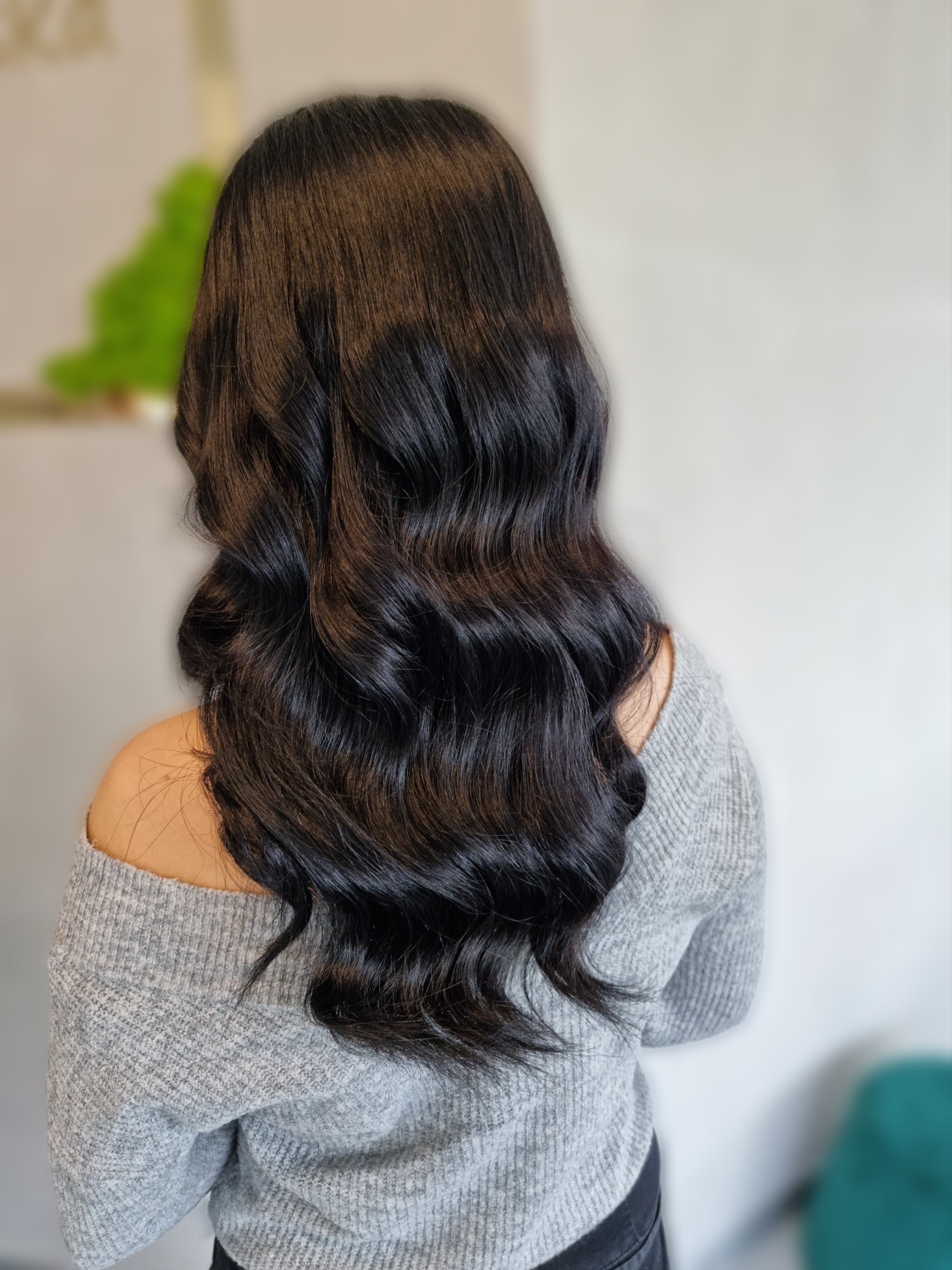 Elegancka fryzura z ciemnych, falowanych włosów, widok z tyłu, wykonana w salonie fryzjerskim w Nowym Sączu. Subtelne fale podkreślają blask włosów.