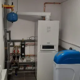 Kompaktowa kotłownia we Wrocławiu z piecem, rozbudowanym systemem rur, zbiornikiem wyrównawczym i zmiękczaczem wody.