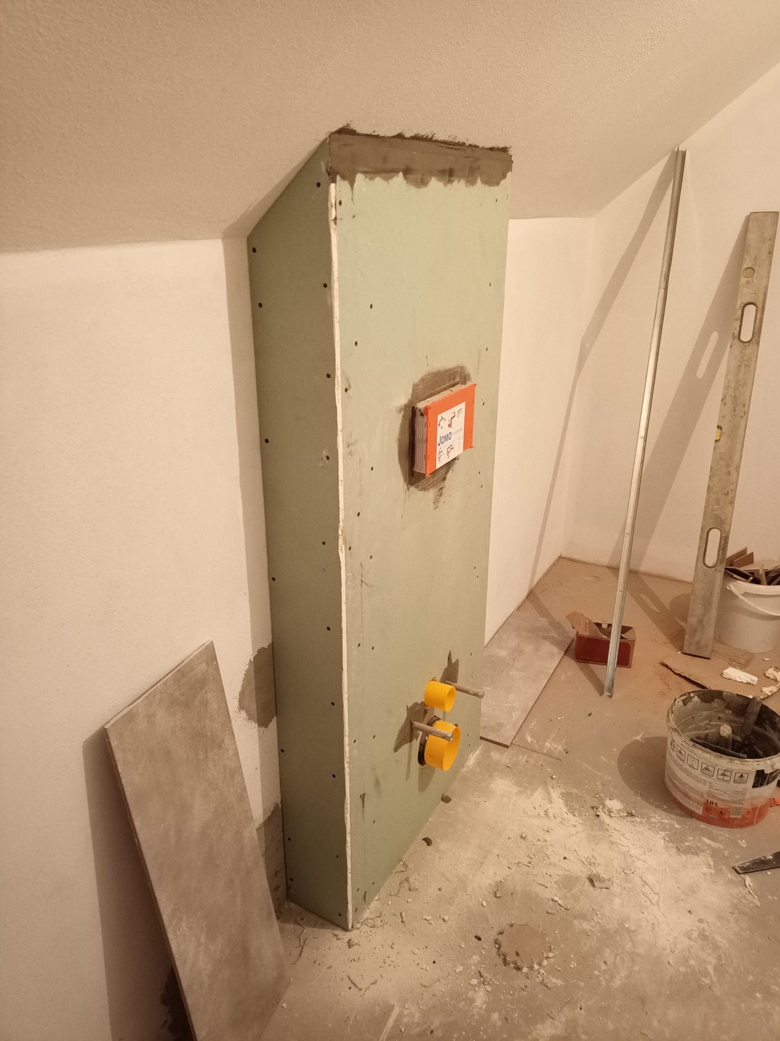 Stelaż podtynkowy obudowany płytą karton gips, z widocznymi przyłączami wodnymi i puszką instalacyjną JOMO, w trakcie prac wykończeniowych łazienki.