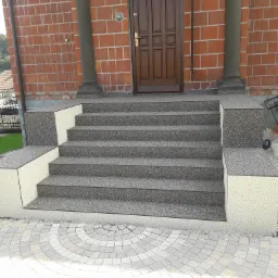 Schody wejściowe wykończone szarą, kamienną posadzką z żywicą, prowadzące do brązowych drzwi wejściowych z numerem 335, na tle ceglanej ściany z kolumnami.