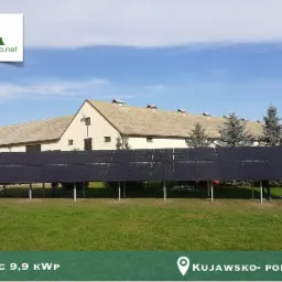 Instalacja paneli słonecznych na metalowej konstrukcji na tle budynku gospodarczego i drzew iglastych, z informacją o mocy 9,9 kWp i lokalizacji Kujawsko-Pomorskie.