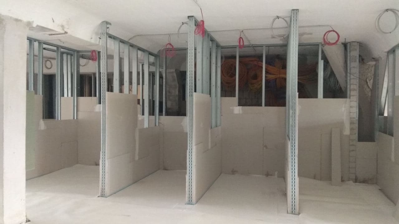 Wnętrze w trakcie tworzenia ścian działowych z płyt gipsowo-kartonowych na metalowym stelażu, widoczne kable elektryczne pod sufitem.