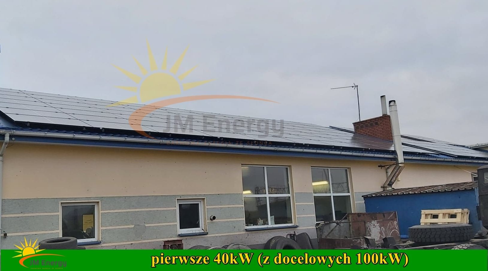 Instalacja paneli słonecznych na dachu budynku z widocznym logo firmy JM Energy oraz informacją o mocy instalacji: pierwsze 40kW z docelowych 100kW.