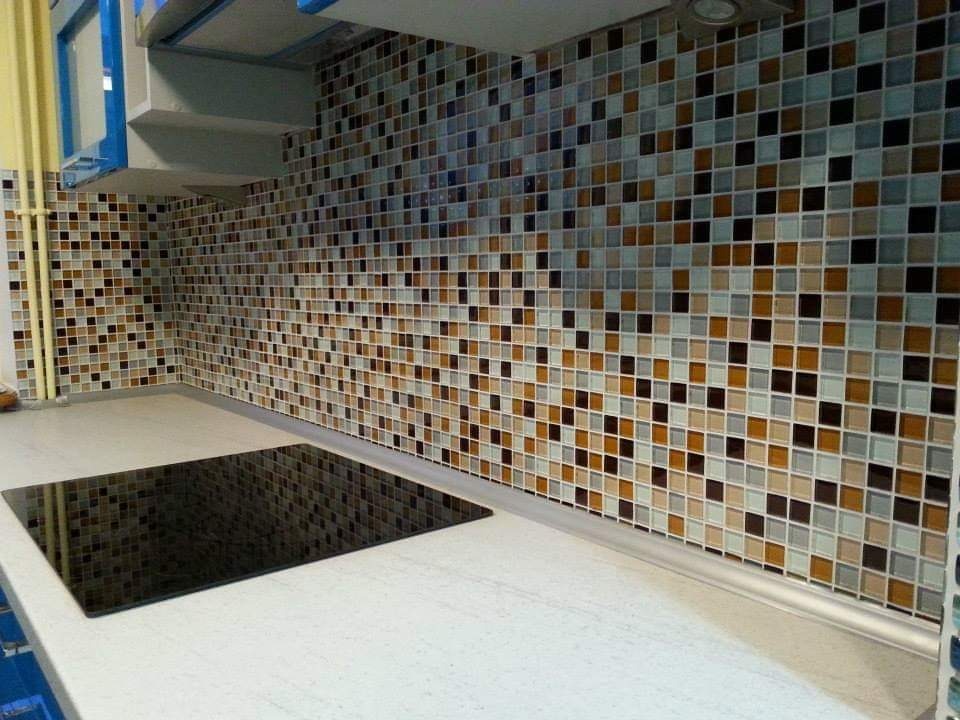 Kuchnia z mozaiką ścienną w odcieniach brązu, beżu, szarości i czerni, uzupełniona blatem z czarną płytą grzewczą.