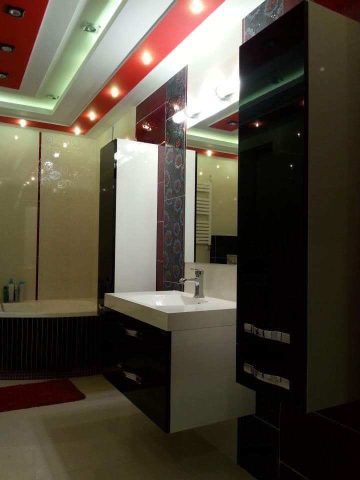 Nowoczesna łazienka z podwieszaną szafką z umywalką, czarno-białymi frontami, oświetleniem punktowym i dekoracyjnymi płytkami na ścianie.