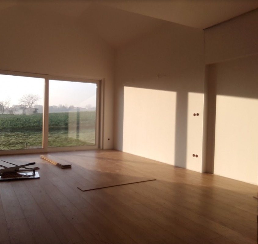 Montaż parkietu w jasnym pokoju z dużym oknem na ogród, widoczne narzędzia i deski podłogowe, popołudniowe światło podkreśla strukturę drewna.