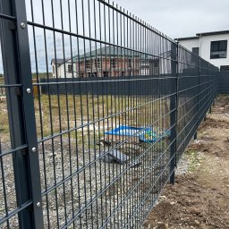 Stalbau - Nowoczesne, grafitowe ogrodzenie panelowe w Górzycy, widok z bliska na łączenie paneli, w tle budowa domu.