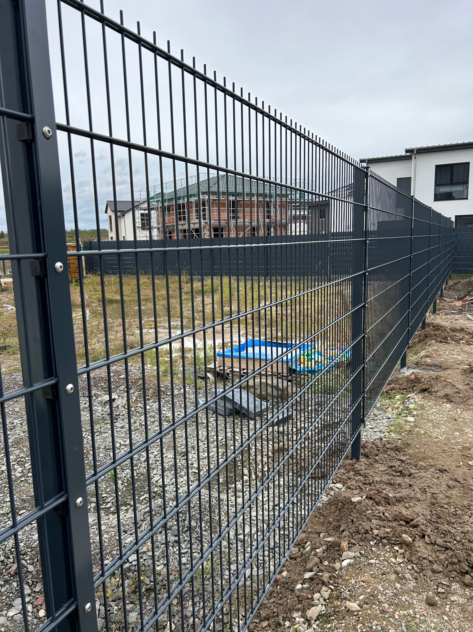 Nowoczesne, grafitowe ogrodzenie panelowe w Górzycy, widok z bliska na łączenie paneli, w tle budowa domu.