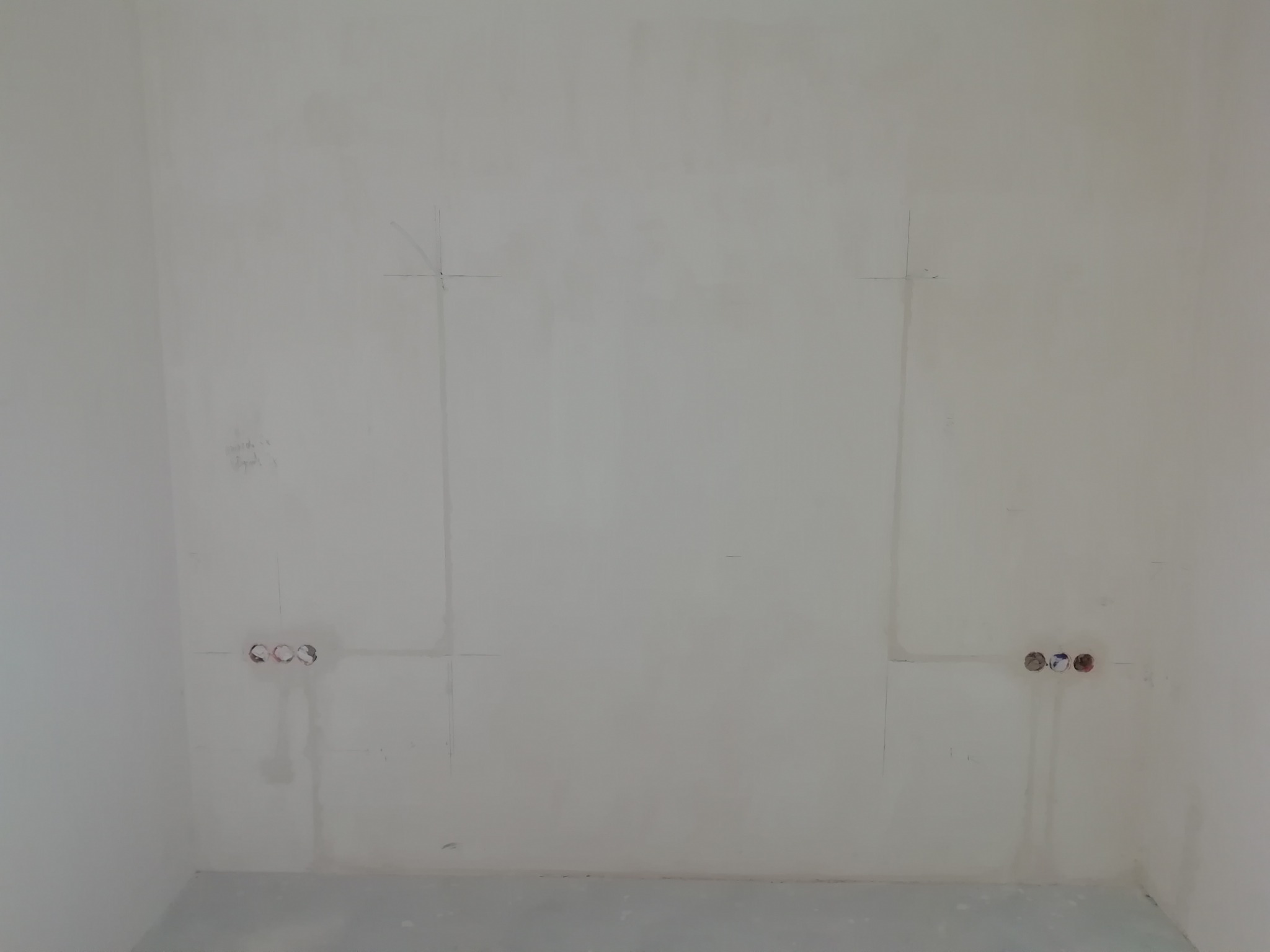 Przygotowana ściana pod montaż telewizora z zaznaczonymi miejscami na kable i gniazdka elektryczne.