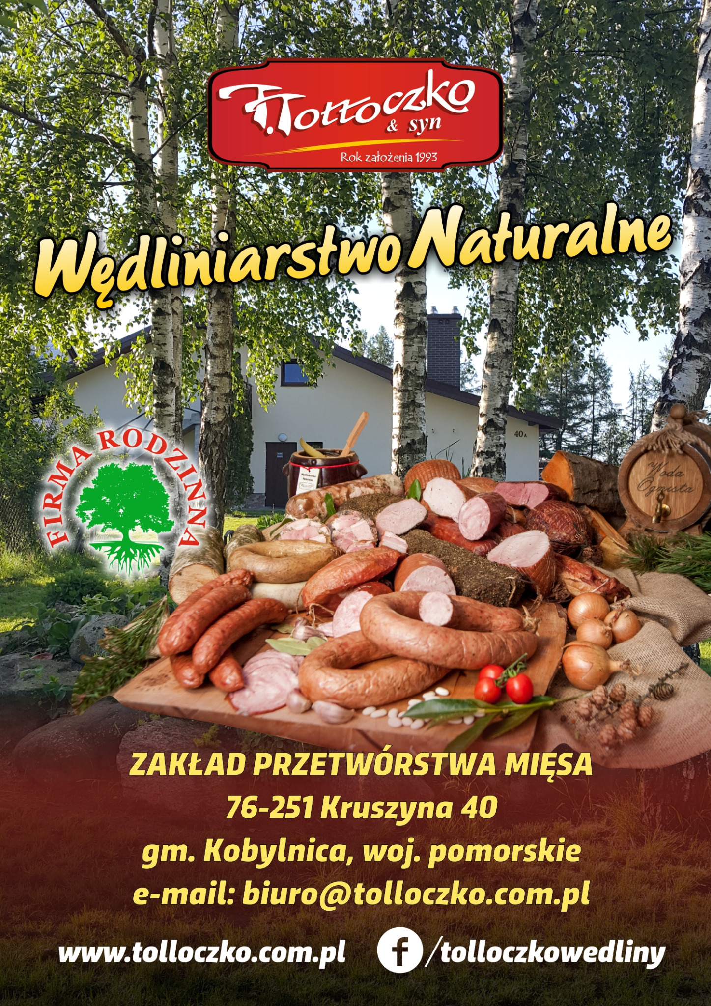 Kompozycja wędlin naturalnych na drewnianym stole z dekoracjami, w tle budynek i brzozy, całość w stylu rustykalnym z akcentami tradycji.