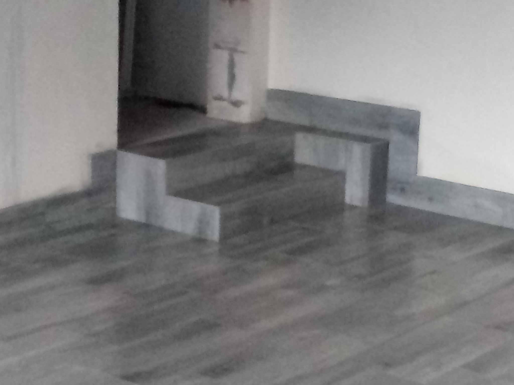 Wykończone marmurowe stopnie prowadzące do pomieszczenia z podłogą z płytek imitujących drewno, widoczne fragmenty ściany z listwą przypodłogową.