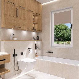 Aleksandra Plucińska - Jasna łazienka z drewnianymi szafkami, umywalką na blacie i wanną przy oknie z widokiem na zieleń. Minimalistyczne czarne akcenty i oświetlenie LED.