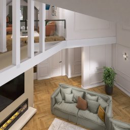 Aleksandra Plucińska - Dwupoziomowy salon z parkietem w jodełkę, szarą sofą i kominkiem pod telewizorem, widziany z góry. Białe ściany z dekoracyjnymi listwami i nowoczesne oświetlenie.
