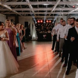 DJ Kiero - WODZIREJ, ANIMATOR, GITARZYSTA - Panna młoda z listą gości i drużba ustawieni w kolejce na sali weselnej, w tle DJ z oświetleniem.