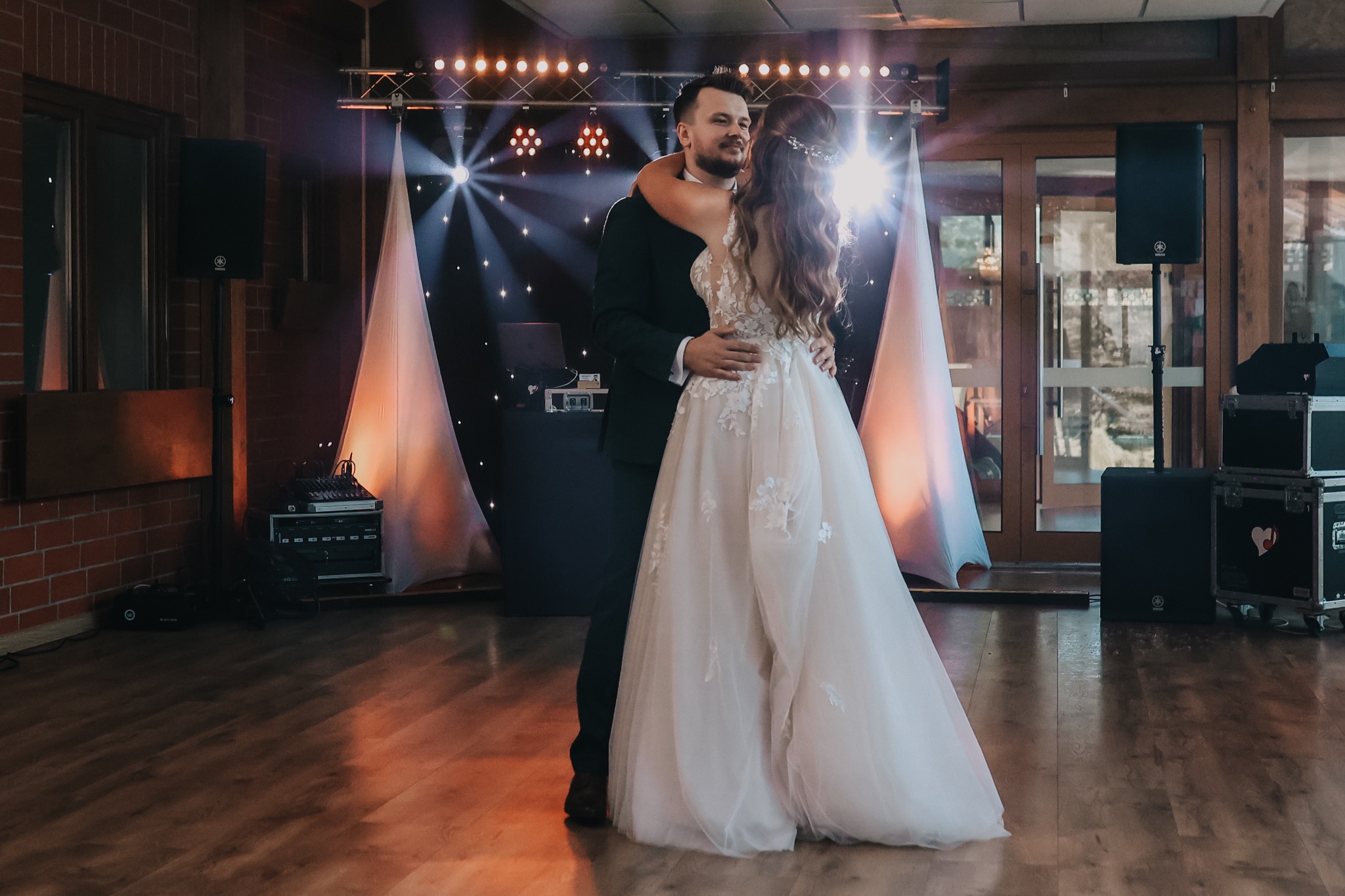 Para młoda w tańcu na parkiecie, w tle scena z nagłośnieniem i oświetleniem, kolumny głośnikowe Yamaha.